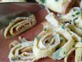 Roladki z jajek, idealne jako makaron keto z jajek, posypane szczypiorkiem, krojoną na desce.