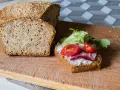 Keto chleb majonezowy przepis: kromka z serkiem, pomidorkami i sałatą obok bochenka z ziarnami.