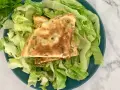 Puszysty omlet z ziołami na talerzu z sałatą.