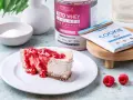 Pyszny sernik keto z malinami, obok słoik Keto Whey Isolate i batonik Keto Cookie. Idealny keto spod do sernika.