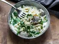 Keto makaron w kremowym sosie z groszkiem i mięsem, nabierany widelcem.