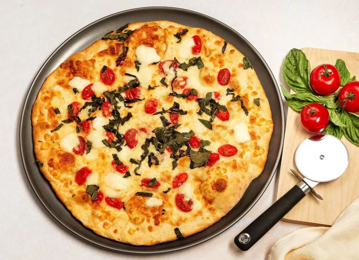 Pyszna pizza z serka wiejskiego, pomidorkami koktajlowymi i bazylią. Idealna na szybki obiad.