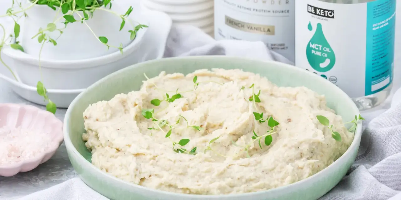 Kremowe puree z kalafiora keto, udekorowane świeżym tymiankiem. Obok miseczka z różową solą i produkty Be Keto.