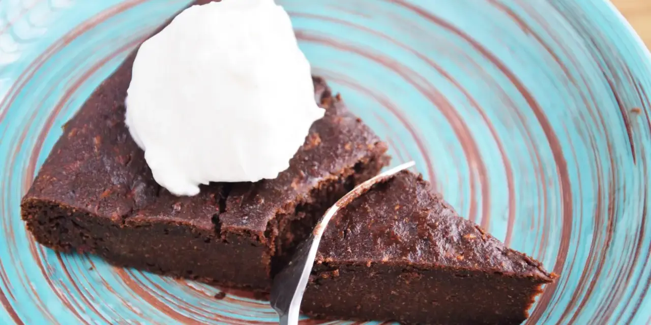 Pyszne keto brownie z cukinii, podane z bitą śmietaną na turkusowym talerzu. Idealne na deser bez wyrzutów sumienia.