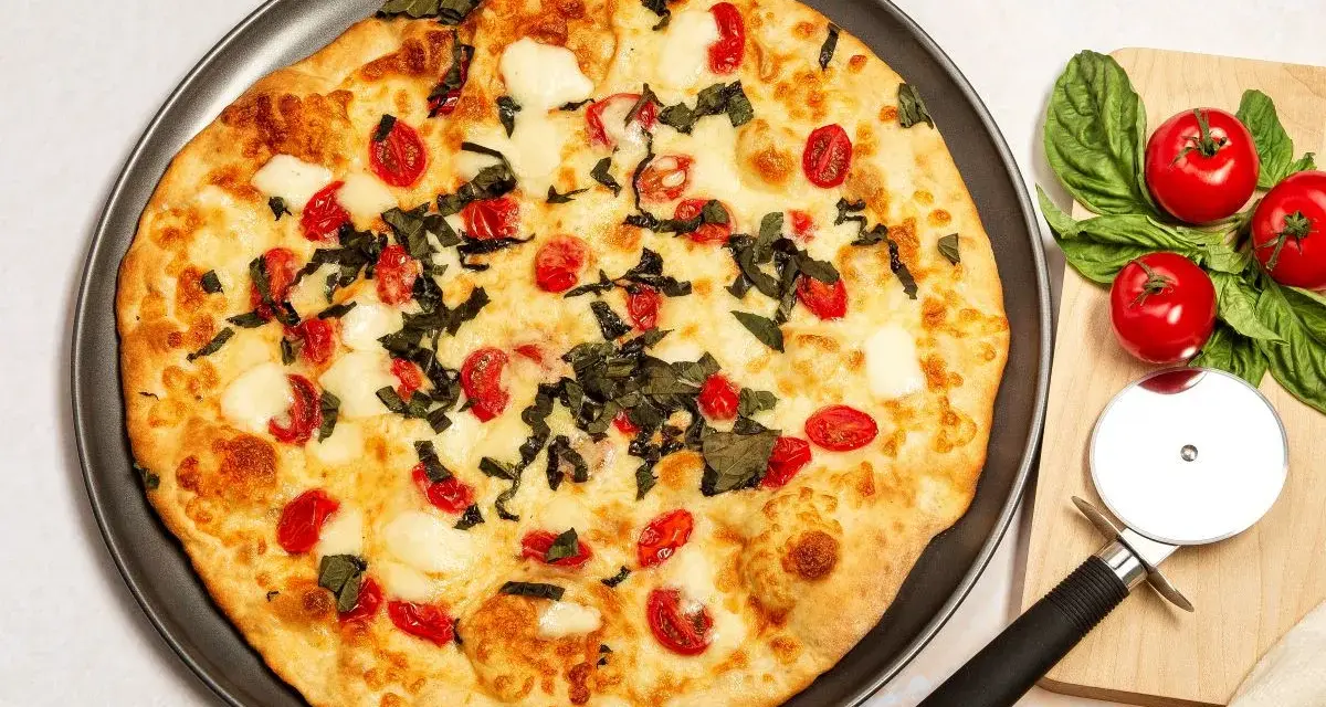 Pyszna pizza z serka wiejskiego, pomidorkami koktajlowymi i bazylią. Idealna na szybki obiad.