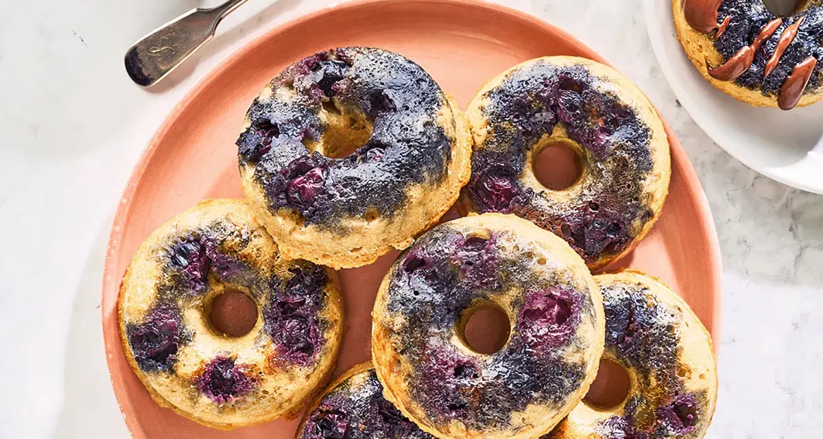 Keto pączki z mąki migdałowej z jagodami na różowym talerzu.