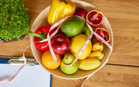 Miska pełna owoców i warzyw, miarka krawiecka. Idealne składniki na zdrowy dieta 500 kcal jadłospis na tydzień.