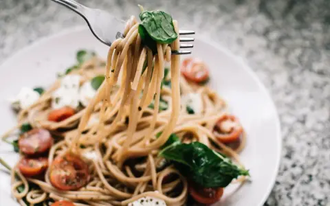 Makaron z pomidorkami i mozzarellą na widelcu. Czy 2500 kcal to dużo? Zależy od apetytu!