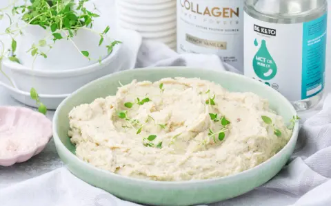 Kremowe puree z kalafiora keto, udekorowane świeżym tymiankiem. Obok miseczka z różową solą i produkty Be Keto.