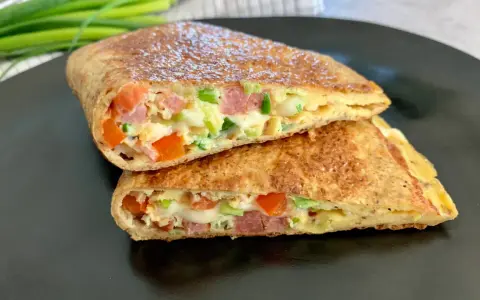 Pyszny keto wrap przepis: jajko, ser, pomidor, szynka i szczypiorek zawinięte w cienki placek. Idealny na szybkie śniadanie lub lunch.