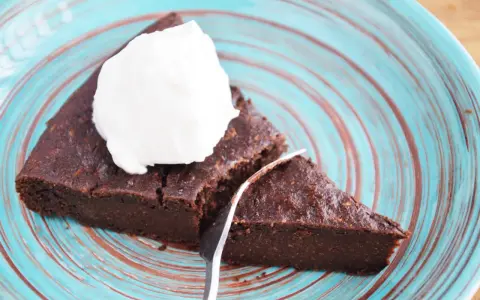 Pyszne keto brownie z cukinii, podane z bitą śmietaną na turkusowym talerzu. Idealne na deser bez wyrzutów sumienia.
