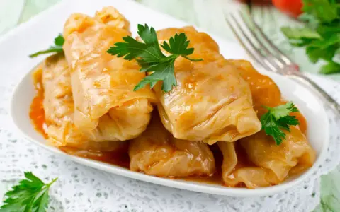 Talerz gołąbków w sosie, udekorowany natką pietruszki. Zastanawiasz się, ile kcal ma gołąbek?