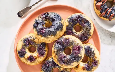 Keto pączki z mąki migdałowej z jagodami na różowym talerzu.