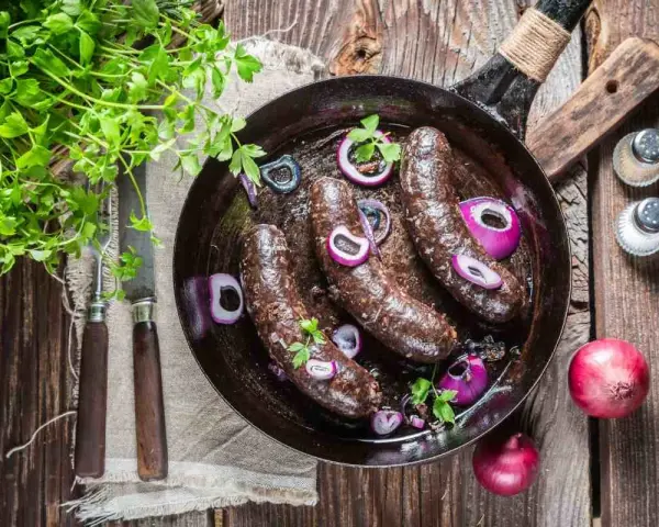 Smażona kaszanka z cebulą na patelni, idealna na keto. Świeża natka pietruszki dodaje aromatu.