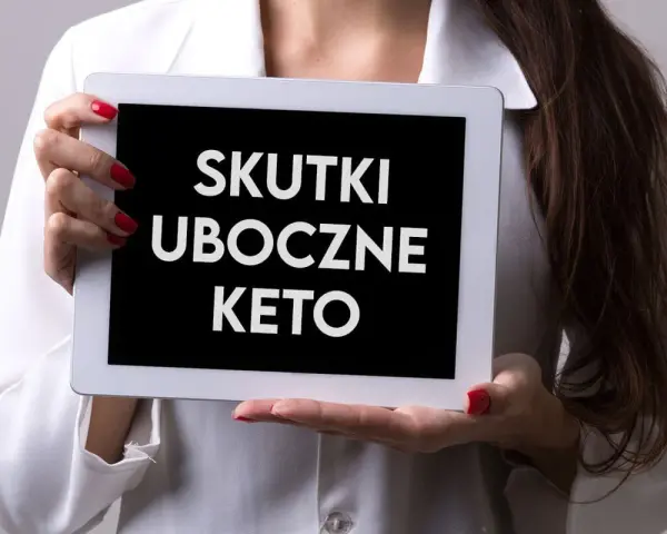 Kobieta w białej bluzce prezentuje tablet z napisem "SKUTKI UBOCZNE KETO".