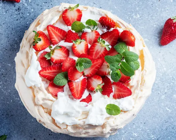Pyszny deser Pavlova z truskawkami, idealny przepis na bezy z 3 białek. Lekka i chrupiąca beza z bitą śmietaną i owocami.