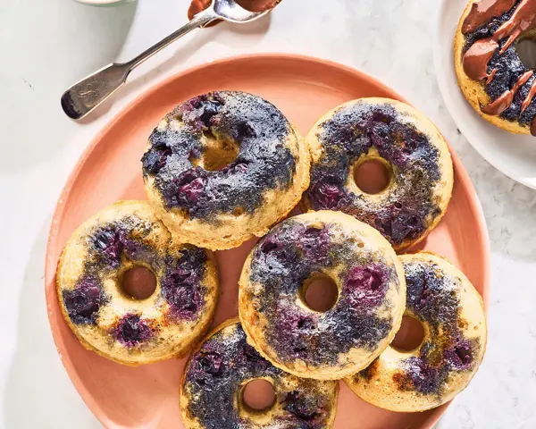 Keto pączki z mąki migdałowej z jagodami na różowym talerzu.