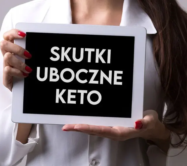 Kobieta w białej bluzce prezentuje tablet z napisem "SKUTKI UBOCZNE KETO".