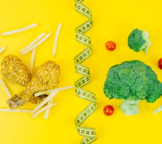 Po lewej frytki i panierowany kurczak, po prawej brokuły i pomidorki. Miarka krawiecka symbolizuje, że dzięki diecie low carb schudłam.