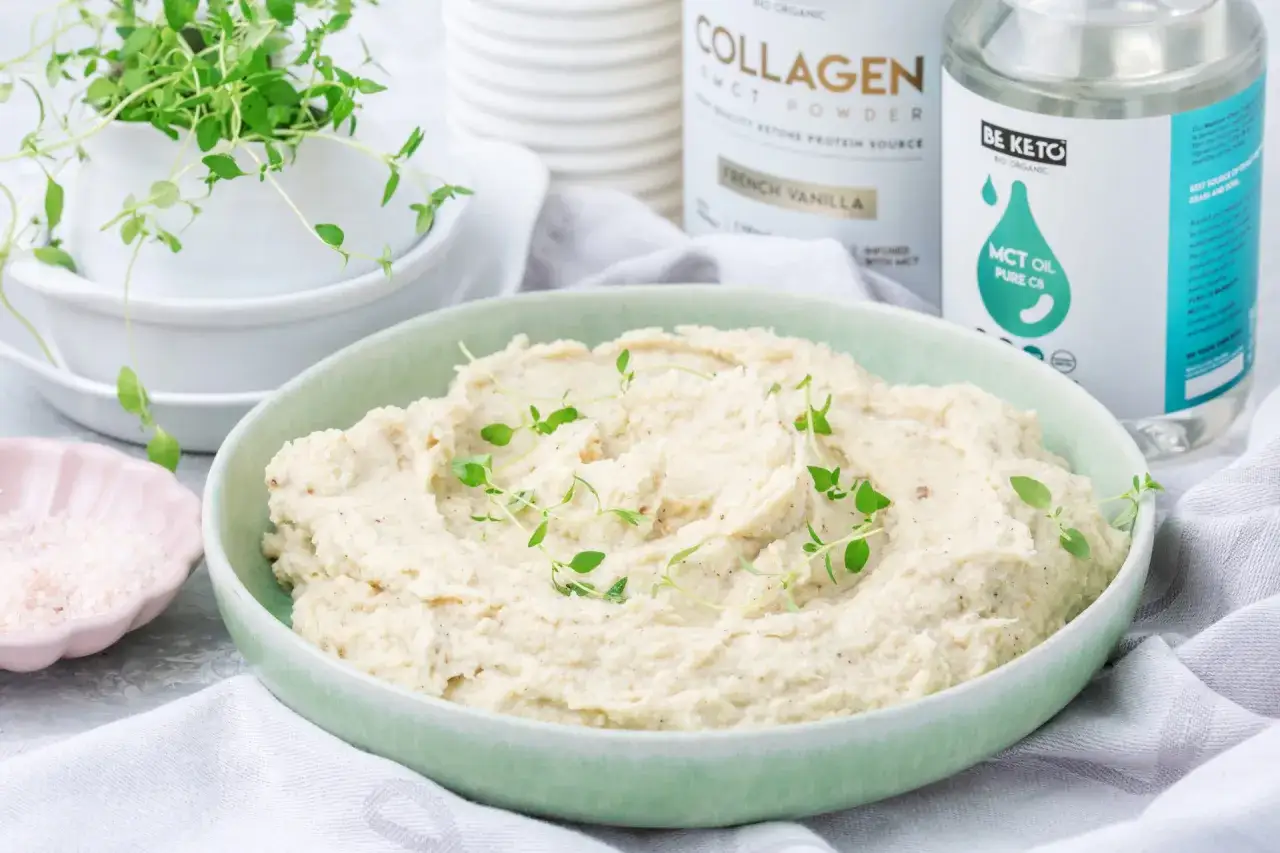 Kremowe puree z kalafiora keto, udekorowane świeżym tymiankiem. Obok różowa sól i produkty keto.
