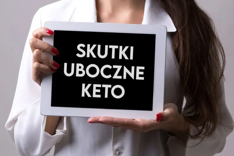 Kobieta w białej bluzce prezentuje tablet z napisem "SKUTKI UBOCZNE KETO".